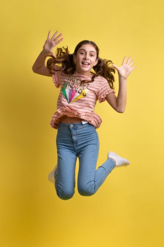 Portrait d'une jeune fille qui saute sur fond jaune