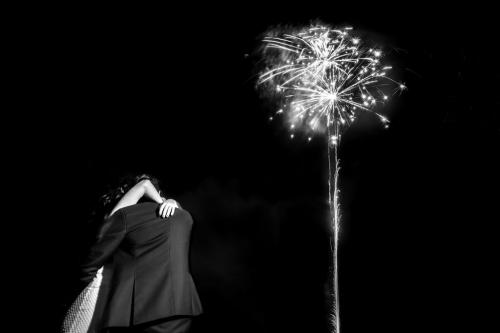 Les mariés s'enlacent sous un feu d'artifice, en noir et blanc