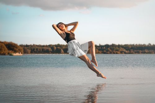 Portrait créatif jeune femme en lévitation sur un lac