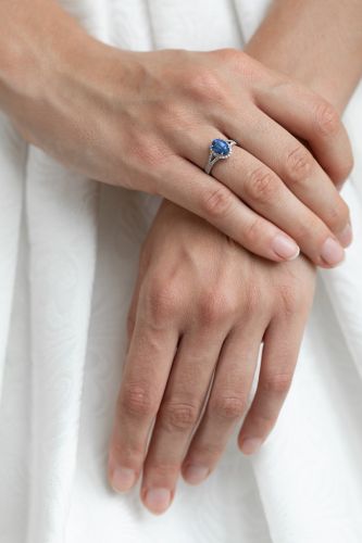 Bague bleue portée avec robe de mariée en fond