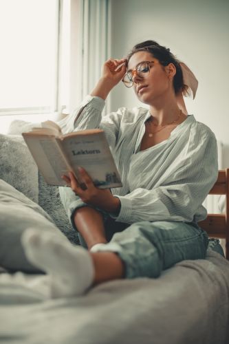 Portrait original d'une jeune femme à lunettes qui lit un livre
